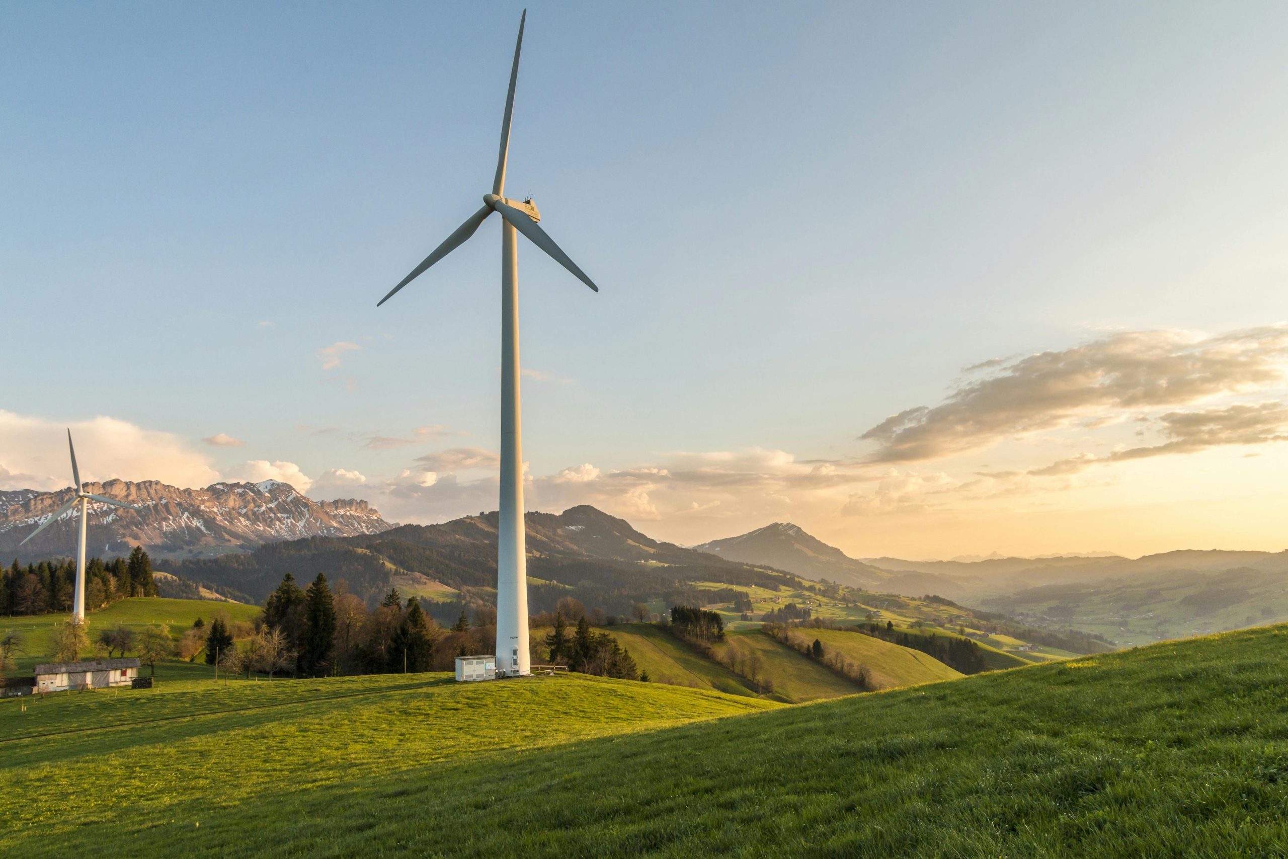 Peaceful countryside with wind turbines during sunset, showcasing sustainable energy.